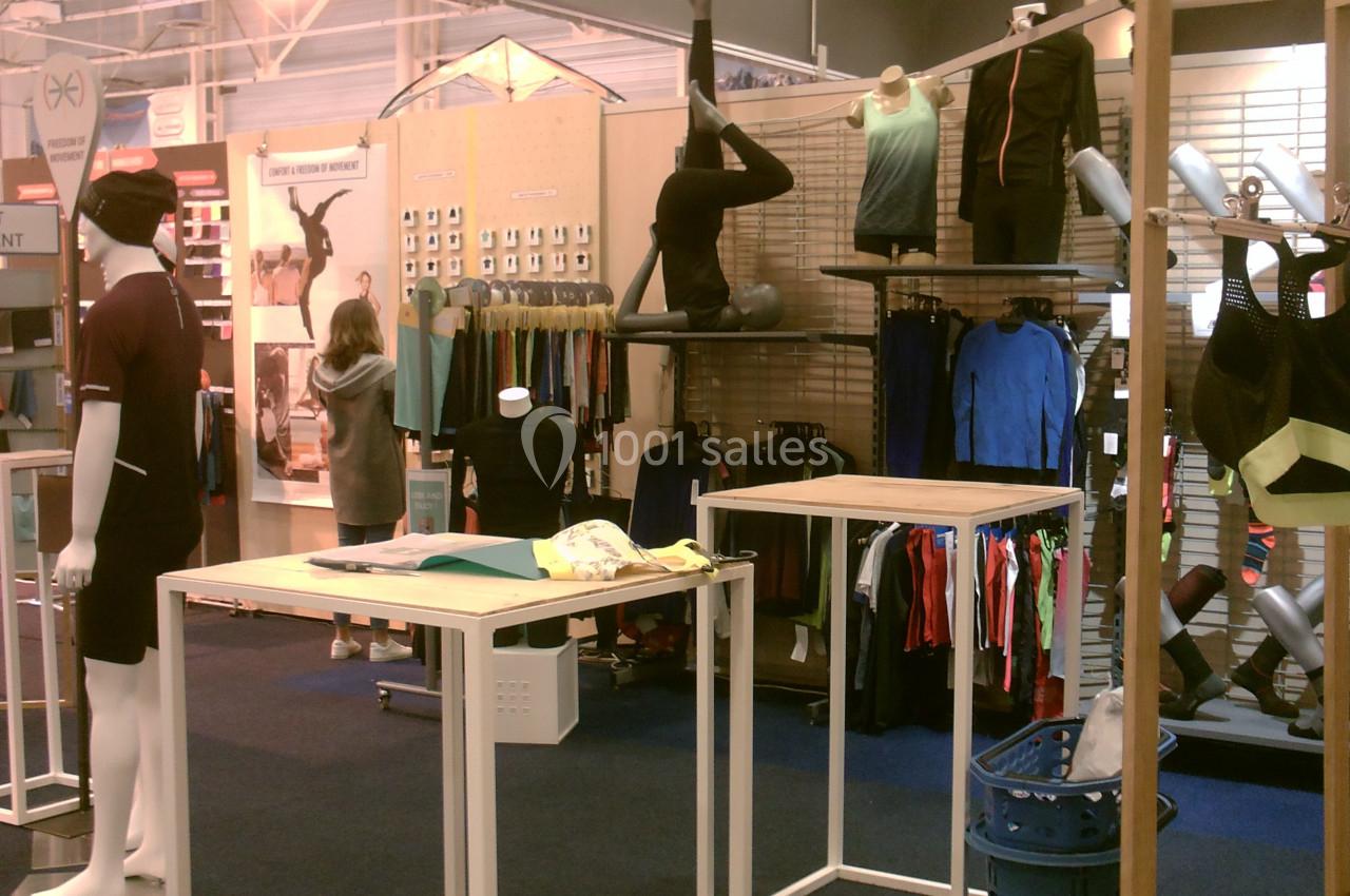 Mannequins et vêtements de sport exposés dans un magasin, avec des étagères et des présentoirs en arrière-plan.