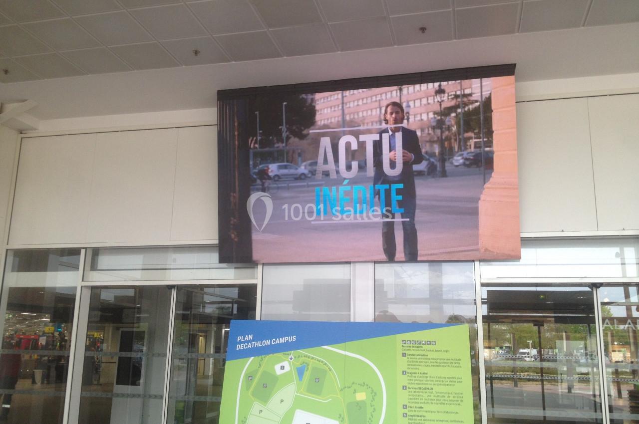 Écran affichant un homme en costume dans un environnement urbain avec le texte ’ACTU INÉDITE’, situé au-dessus d'un plan.
