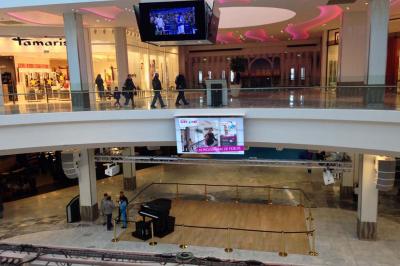 Un bus stationné de nuit devant un bâtiment illuminé, avec des passants en arrière-plan.