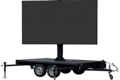 Un bus stationné de nuit devant un bâtiment illuminé, avec des passants en arrière-plan.