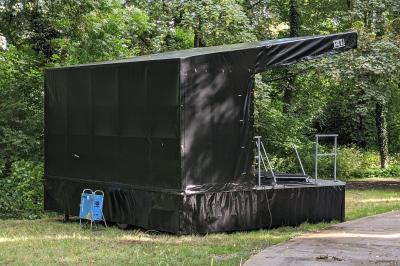 Un bus stationné de nuit devant un bâtiment illuminé, avec des passants en arrière-plan.