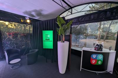 Un bus stationné de nuit devant un bâtiment illuminé, avec des passants en arrière-plan.