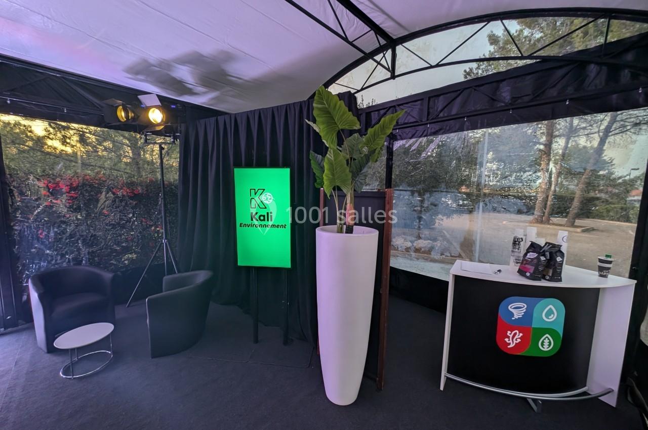 Espace intérieur avec fauteuils, écran affichant ’Kali Environnement’, plante décorative et comptoir d'accueil.