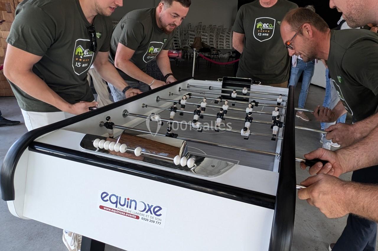 Des personnes jouent au baby-foot dans un espace intérieur, concentrées sur la partie en cours.