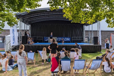 Un bus stationné de nuit devant un bâtiment illuminé, avec des passants en arrière-plan.
