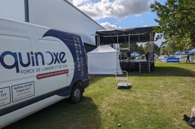 Un bus stationné de nuit devant un bâtiment illuminé, avec des passants en arrière-plan.