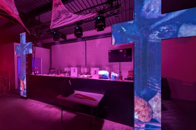 Un bus stationné de nuit devant un bâtiment illuminé, avec des passants en arrière-plan.