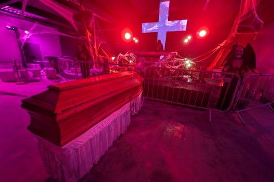 Un bus stationné de nuit devant un bâtiment illuminé, avec des passants en arrière-plan.