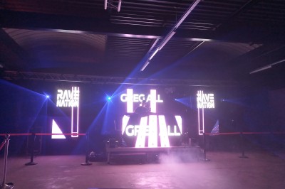 Un bus stationné de nuit devant un bâtiment illuminé, avec des passants en arrière-plan.