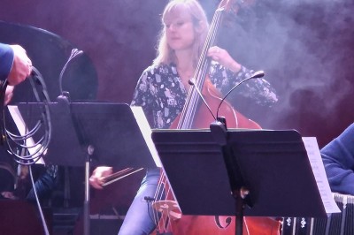 Un bus stationné de nuit devant un bâtiment illuminé, avec des passants en arrière-plan.