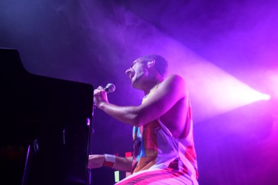 Un bus stationné de nuit devant un bâtiment illuminé, avec des passants en arrière-plan.
