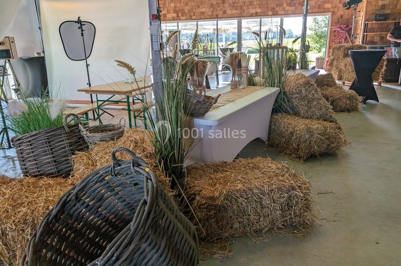 Décoration rustique avec bottes de paille, paniers en osier et plantes dans un espace intérieur lumineux.