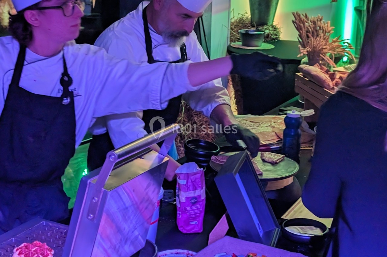 Deux chefs préparent des plats sur des appareils de cuisson lors d'un événement culinaire.