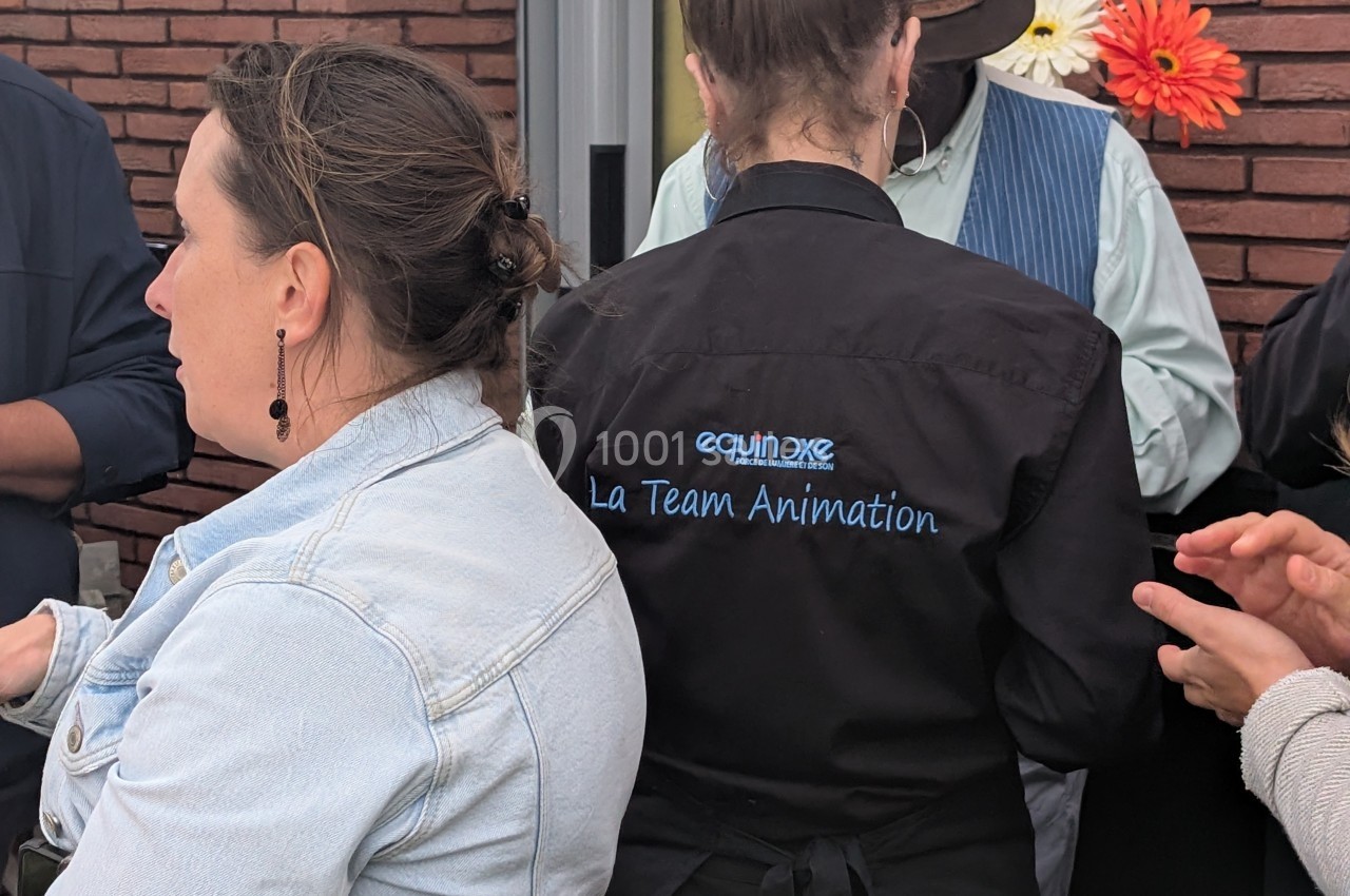 Une femme portant une chemise noire avec l'inscription ’La Team Animation’ est entourée de personnes en discussion.