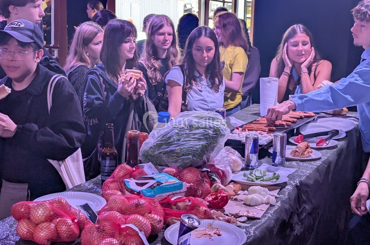 Des personnes se servent à un buffet avec des légumes, du pain et des boissons sur une table décorée.