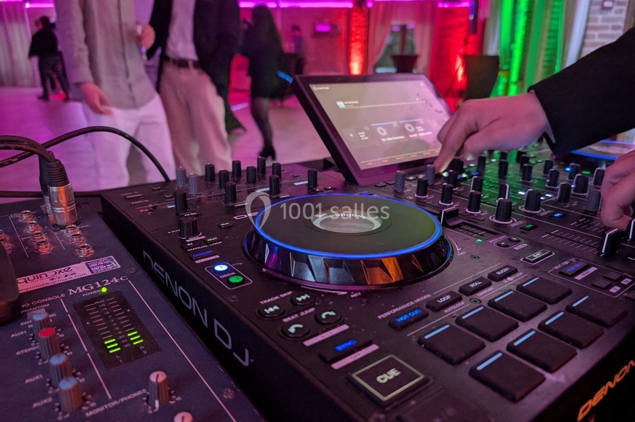 Table de mixage Denon DJ utilisée lors d'un événement avec des lumières colorées en arrière-plan.