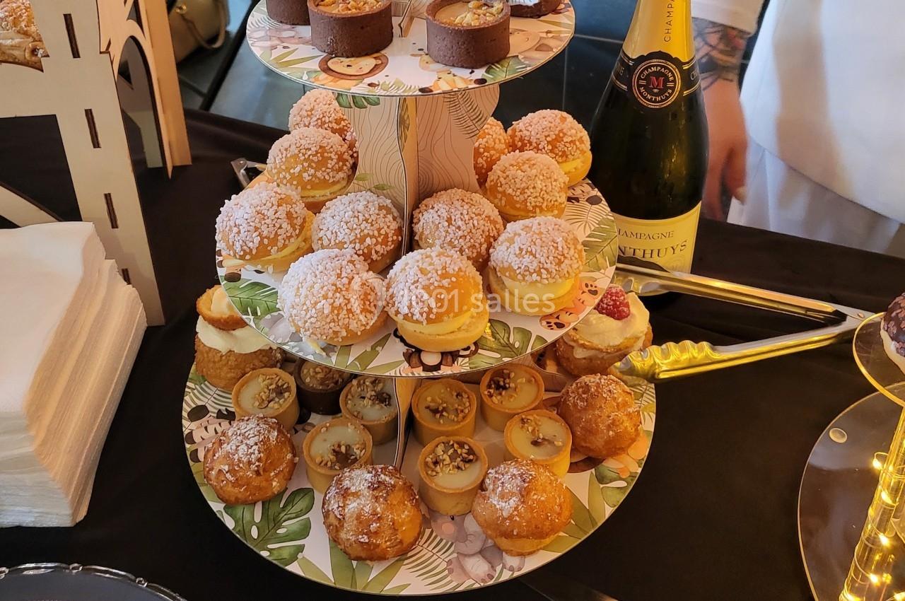Plateau de desserts variés comprenant des choux, des tartelettes et des pâtisseries, accompagné d'une bouteille de champagne.