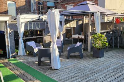 Miniature Location salle Mouscron (Hainaut) - Au Festival de Mouscron  #66 Terrasse en bois avec fauteuils, pergola à rideaux blancs, plantes en pot et mur en briques en arrière-plan.