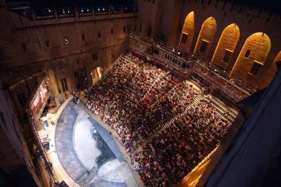 Vue nocturne d'un jardin avec des invités rassemblés lors d'un événement, éclairé par des lumières chaleureuses.