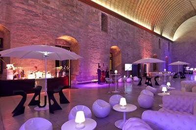 Vue nocturne d'un jardin avec des invités rassemblés lors d'un événement, éclairé par des lumières chaleureuses.