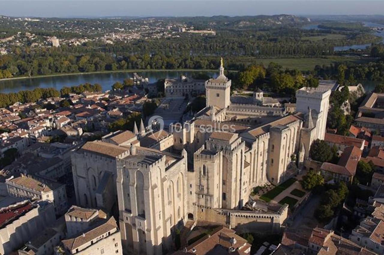 Vue aérienne du Palais des Papes à Avignon, entouré de bâtiments historiques et bordé par le Rhône.