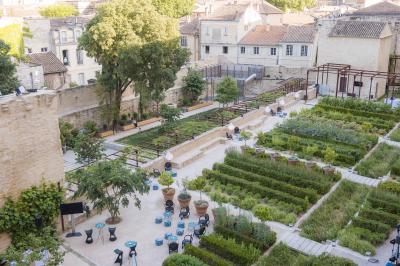 Vue nocturne d'un jardin avec des invités rassemblés lors d'un événement, éclairé par des lumières chaleureuses.