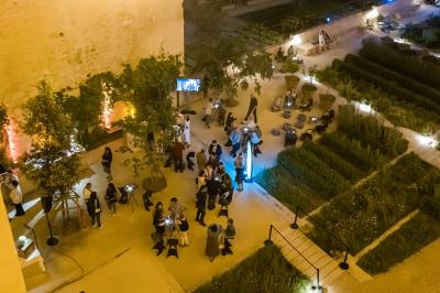 Vue nocturne d'un jardin avec des invités rassemblés lors d'un événement, éclairé par des lumières chaleureuses.