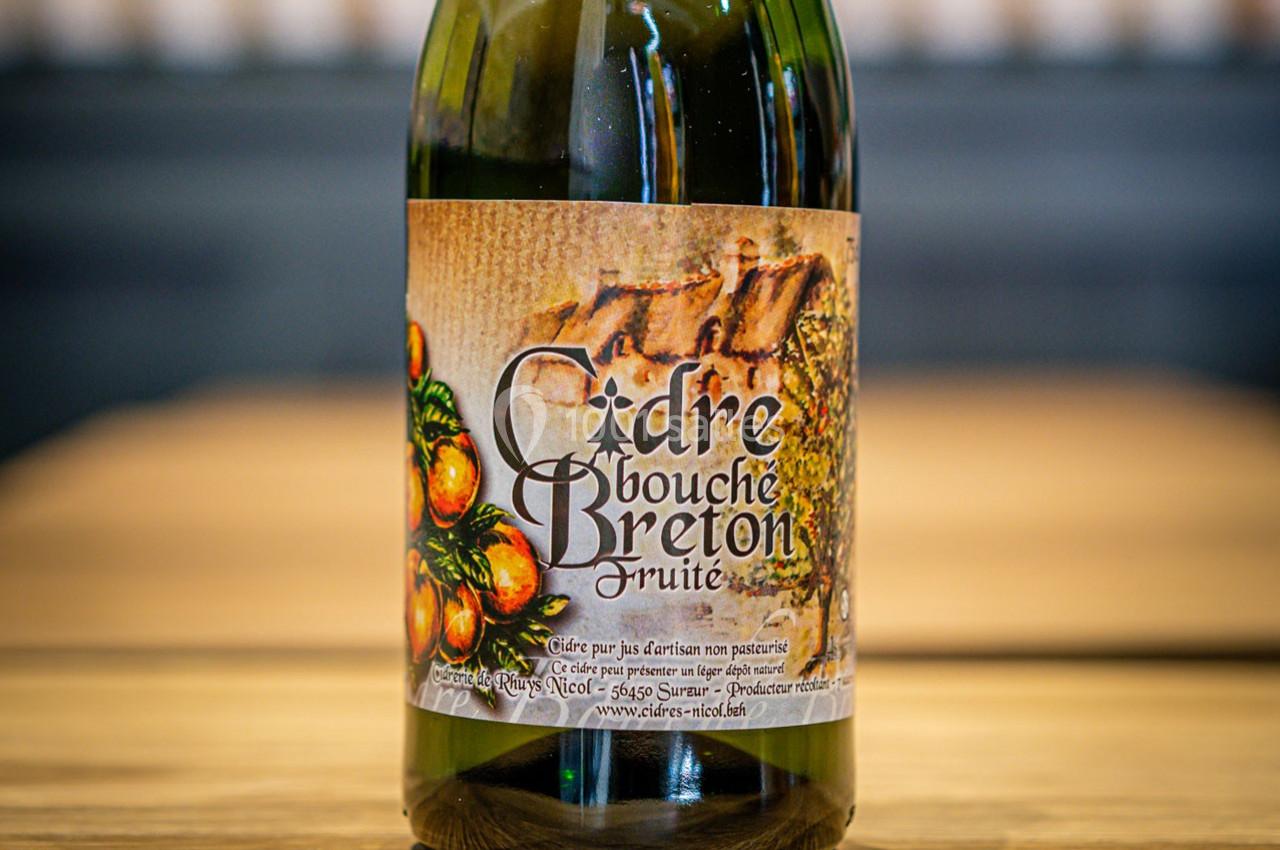 Bouteille de cidre bouché breton fruité avec une étiquette illustrée de pommes et de motifs rustiques.