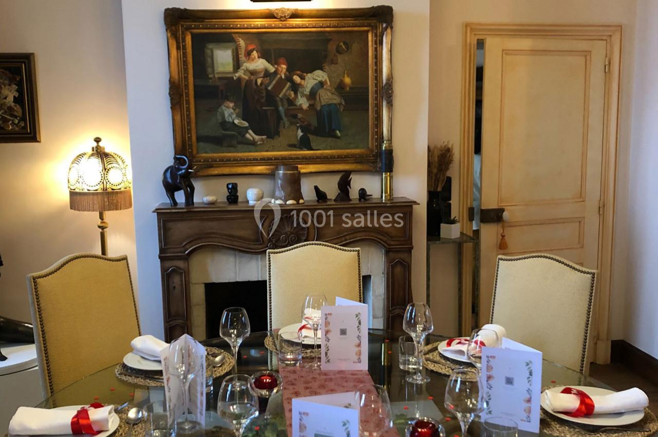Table dressée avec vaisselle et décorations festives dans une salle à manger élégante, ornée d'un tableau classique au mur.
