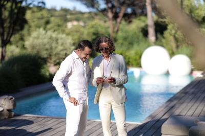 Miniature Robin Geyer - Magicien Professionnel Français #7 Deux femmes en robes rouges scintillantes lèvent les bras en souriant, entourées d'étincelles et de fumée.