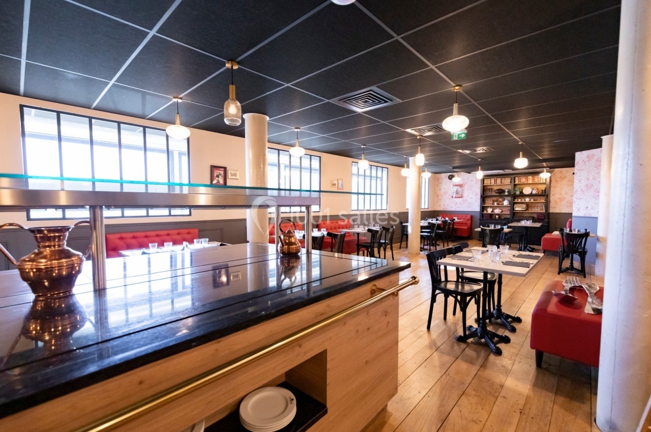Salle de restaurant lumineuse avec tables dressées, banquettes rouges et décoration moderne.