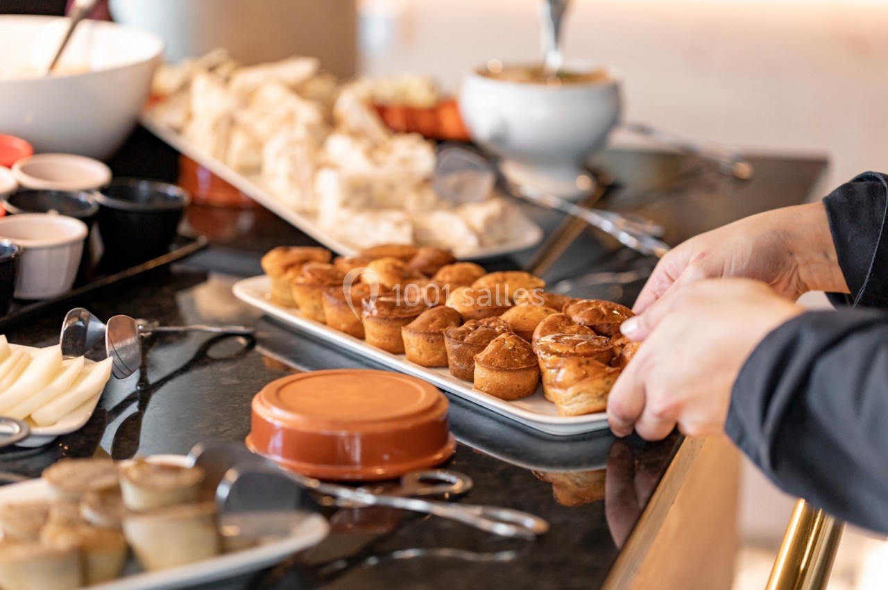 Plateau de petits gâteaux dorés disposés sur une table de buffet avec d'autres plats en arrière-plan.