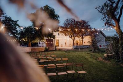 Chambre lumineuse avec lit double, fauteuil beige, fenêtre ouverte sur un paysage et décoration murale en osier.