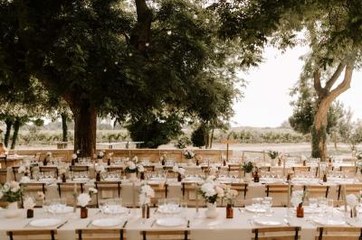 Chambre lumineuse avec lit double, fauteuil beige, fenêtre ouverte sur un paysage et décoration murale en osier.