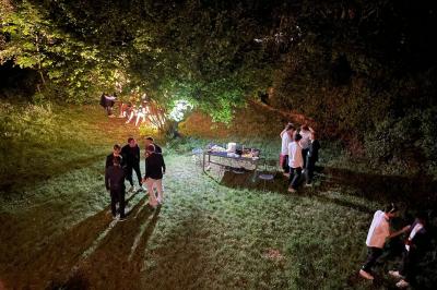 Miniature Location salle Châtenay-Malabry (Hauts-de-Seine) - La Demeure de Verrières #11 Groupe de personnes discutant et partageant un moment convivial en extérieur, éclairé par une lumière nocturne.
