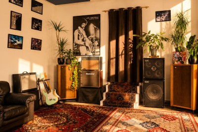 Salle sombre avec éclairage rouge et bleu, une estrade avec équipement audio et un tapis mural en arrière-plan.