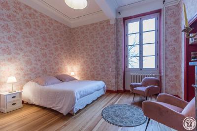 Piscine rectangulaire entourée de dalles et pelouse, avec un grand arbre en arrière-plan sous un ciel dégagé.