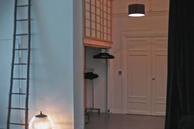 Miniature Location salle Paris 20 (Paris) - Studio 7 #16 Salle avec des tables et chaises noires disposées en U, projection d’un paon coloré sur un mur blanc, rideaux noirs à droite.