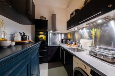 Miniature Location salle Paris 20 (Paris) - Studio 7 #11 Salle avec des tables et chaises noires disposées en U, projection d’un paon coloré sur un mur blanc, rideaux noirs à droite.