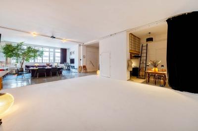 Miniature Location salle Paris 20 (Paris) - Studio 7 #12 Salle avec des tables et chaises noires disposées en U, projection d’un paon coloré sur un mur blanc, rideaux noirs à droite.