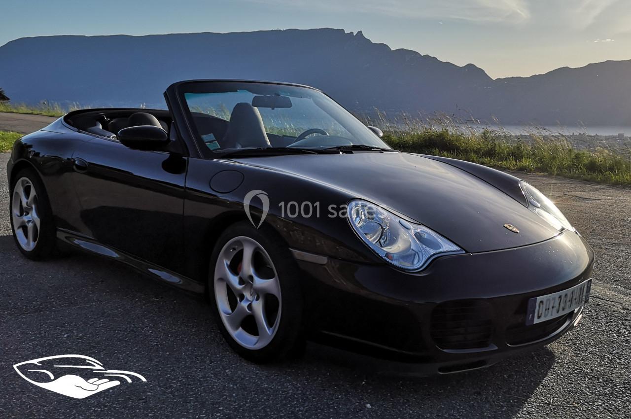 Photo David J. Location #13 Voiture décapotable noire stationnée sur une route, avec des montagnes en arrière-plan sous un ciel clair.