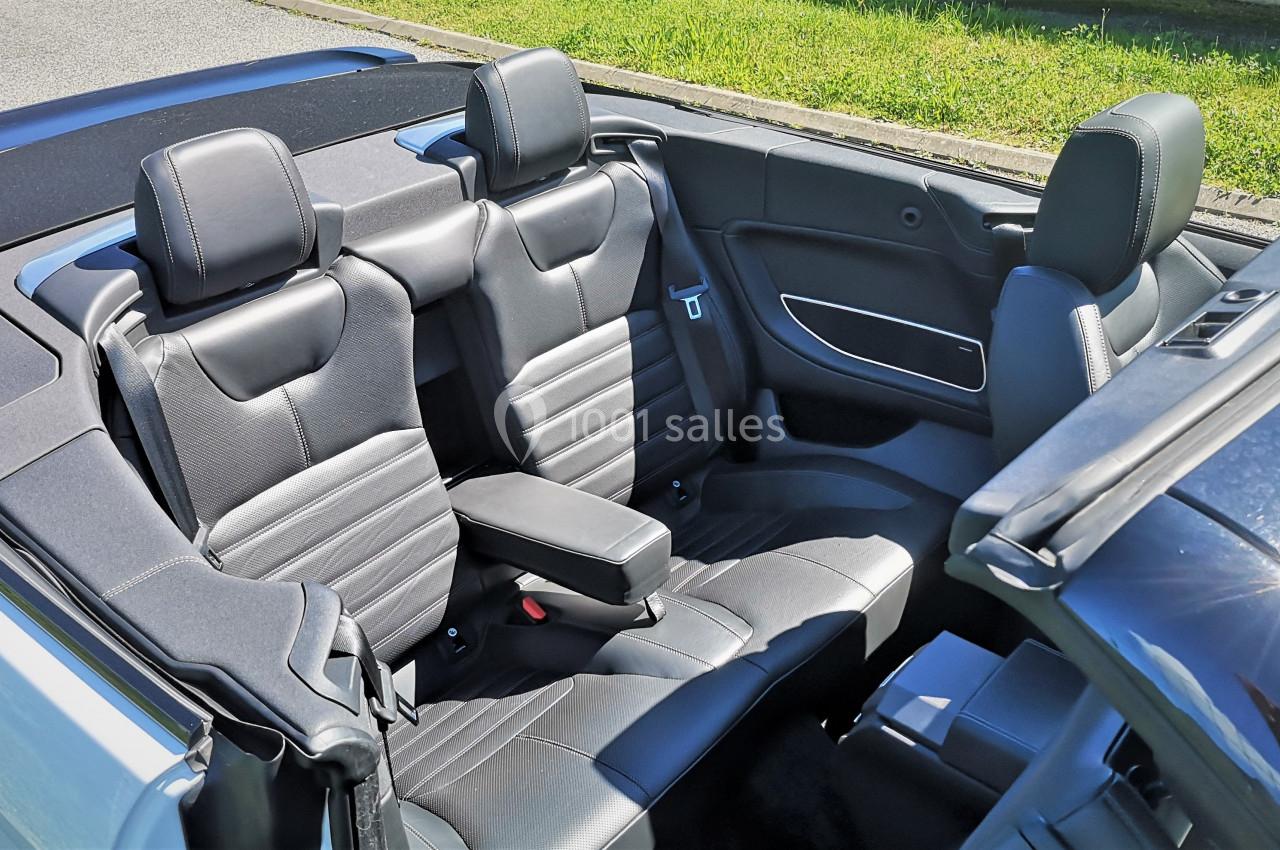 Photo David J. Location #10 Intérieur d'une voiture décapotable avec sièges en cuir noir, vue sur les places arrière et l'appui-bras central.