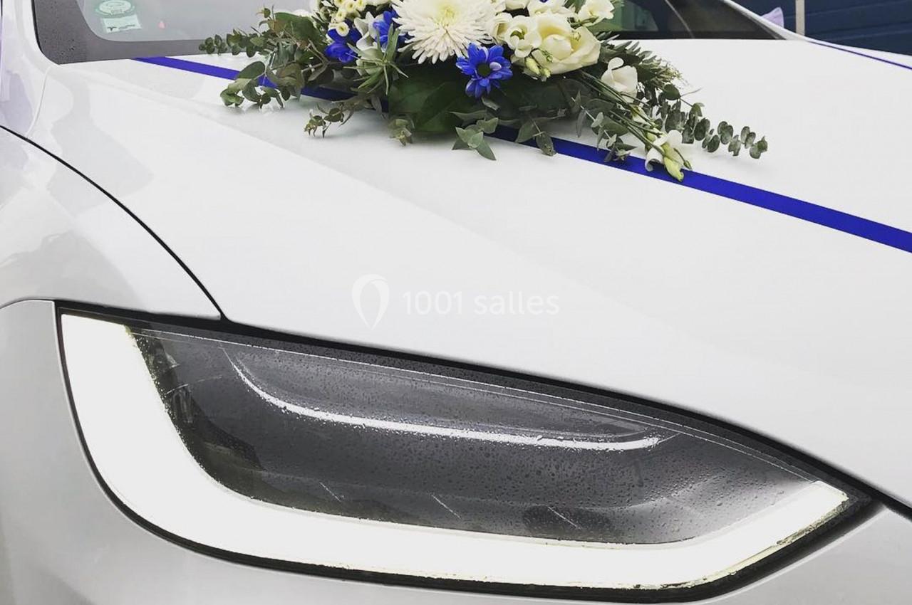 Photo David J. Location #3 Gros plan sur le phare avant d'une voiture blanche décorée d'un bouquet de fleurs et d'un ruban bleu.