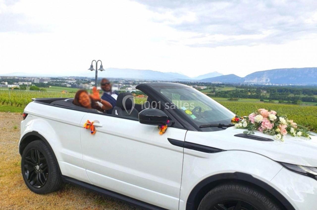 Photo David J. Location #5 Une voiture décapotable blanche décorée de fleurs, garée dans un paysage de vignobles avec des montagnes en arrière-plan.