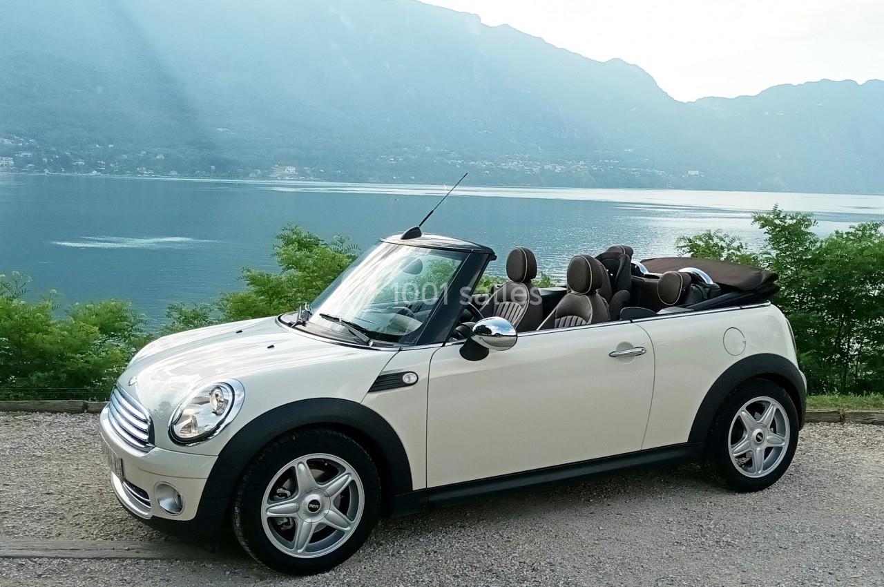 Photo David J. Location #16 Voiture décapotable blanche stationnée devant un lac entouré de montagnes et de végétation.