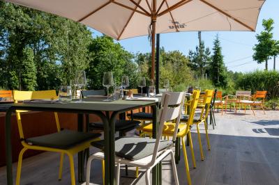 Vue aérienne d'un parking vide entouré de végétation, avec quelques voitures stationnées et un ciel dégagé.