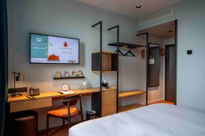 Vue aérienne d'un parking vide entouré de végétation, avec quelques voitures stationnées et un ciel dégagé.