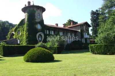 Salle de restaurant avec tables rondes dressées, nappes blanches, chaises en bois et éclairage tamisé.