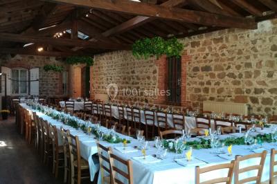 Salle de restaurant avec tables rondes dressées, nappes blanches, chaises en bois et éclairage tamisé.