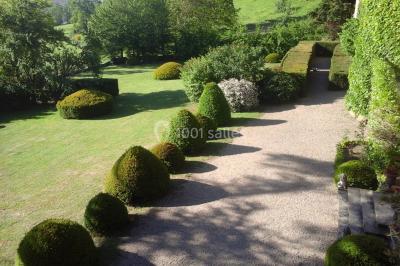 Salle de restaurant avec tables rondes dressées, nappes blanches, chaises en bois et éclairage tamisé.